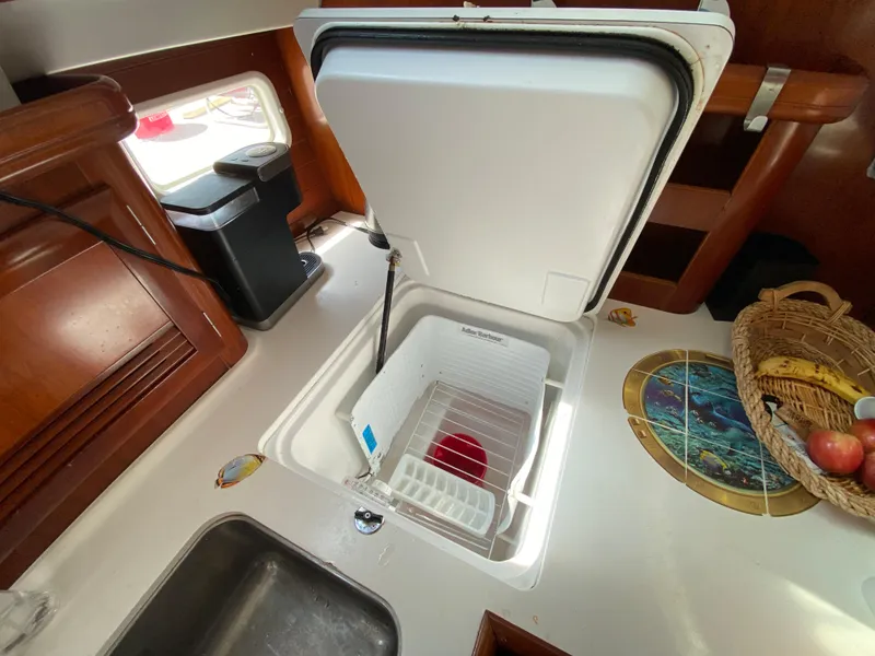 Slide: The Image of Galley of 2003 Beneteau 423 sailboat with open fridge, sink, and fruit basket. - 43