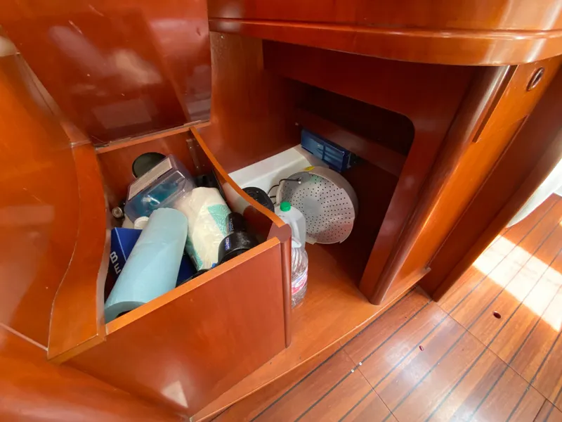 Slide: The Image of Storage compartments inside a 2003 Beneteau 423 yacht, featuring wooden cabinetry and various items. - 48