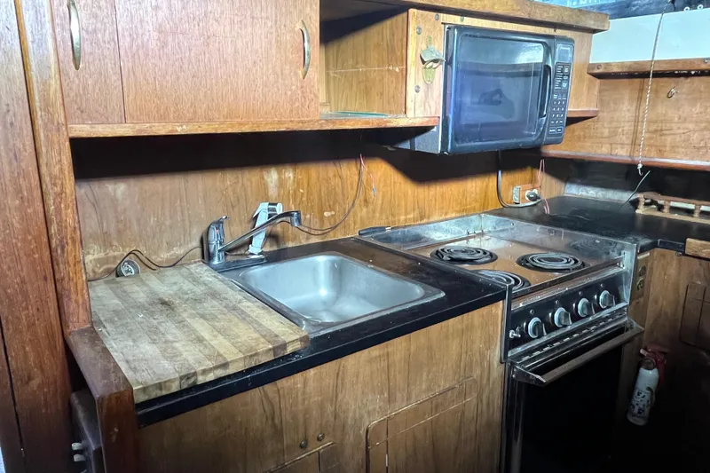 Slide: The Image of 1976 Fiberform 34 boat kitchen with stove, sink, microwave, and wooden cabinetry. - 12