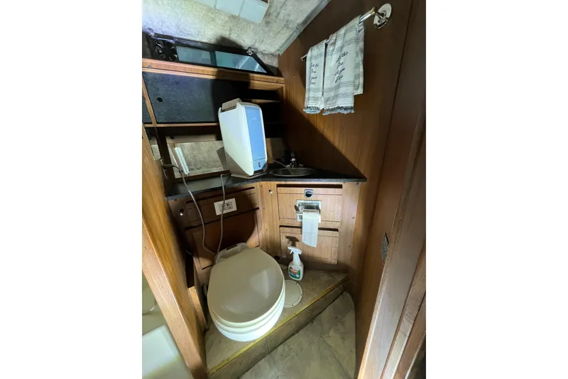 Slide: The Image of 1976 Fiberform 34 boat bathroom with toilet, sink, and wooden cabinetry. - 13
