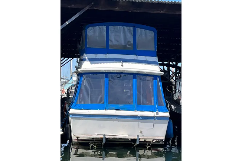 Slide: The Image of 1976 Fiberform 34 boat with blue canopy docked in a marina. - 24