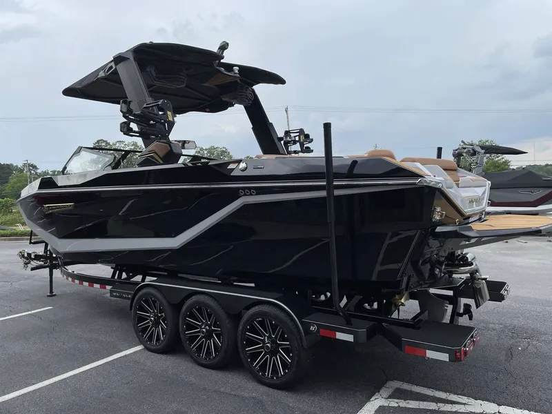 Slide: The Image of Black 2026 Nautique G25 boat on trailer outdoors. - 20