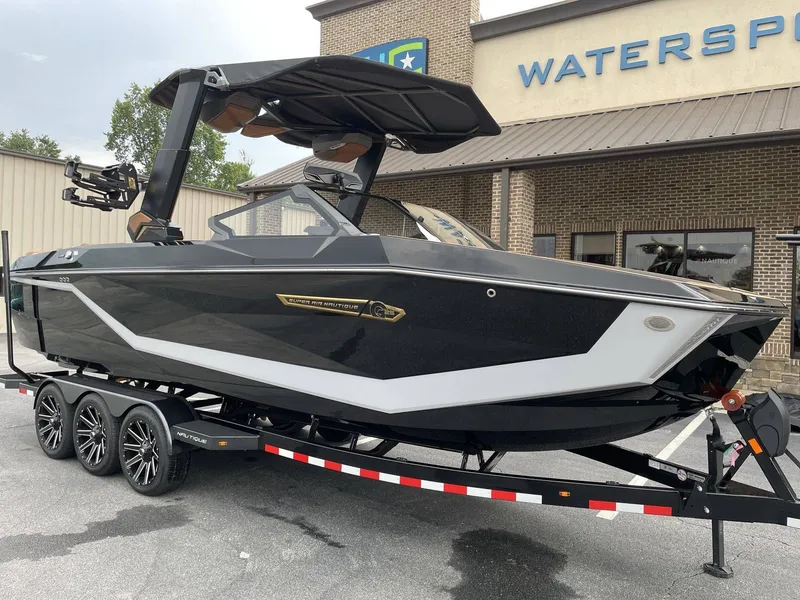 Slide: The Image of 2026 Nautique G25 boat on trailer outside watersports store. - 25