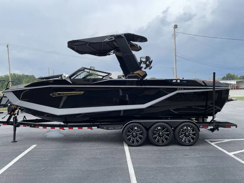 Slide: The Image of Black 2026 Nautique G25 boat on trailer outdoors. - 3