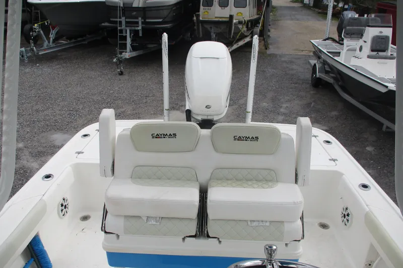 Slide: The Image of 2020 Caymas 28 HB boat interior with cushioned seating and motor, parked on gravel. - 8