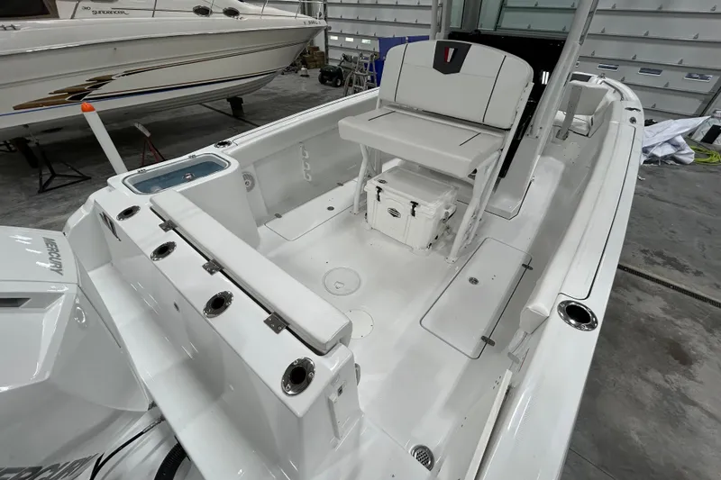 Slide: The Image of 2026 Wellcraft 243 Fisherman boat interior with seating, storage, and Mercury engine in a garage. - 5