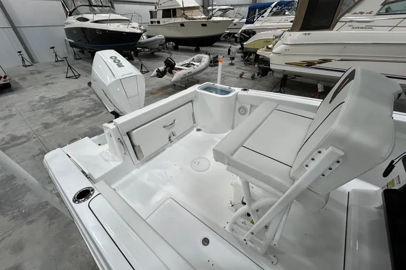 Slide: The Image of 2026 Wellcraft 243 Fisherman boat interior with seating and motor in a showroom. - 6