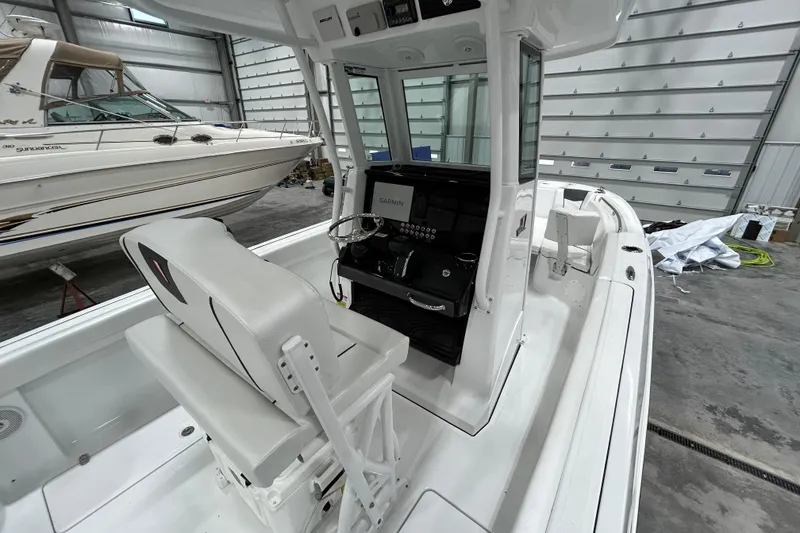 Slide: The Image of 2026 Wellcraft 243 Fisherman boat interior with helm and seating in a storage facility. - 8