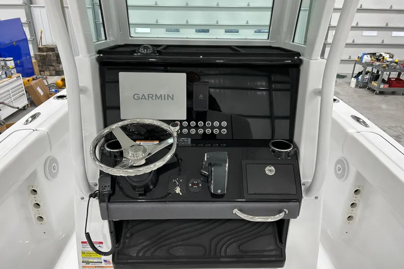 Slide: The Image of 2026 Wellcraft 243 Fisherman helm with Garmin display and modern controls in a garage setting. - 9