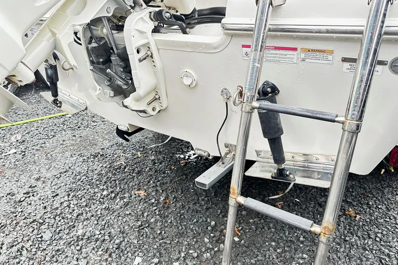 Slide: The Image of 2017 Sea Chaser 22 HFC boat with ladder and engine details on gravel. - 12