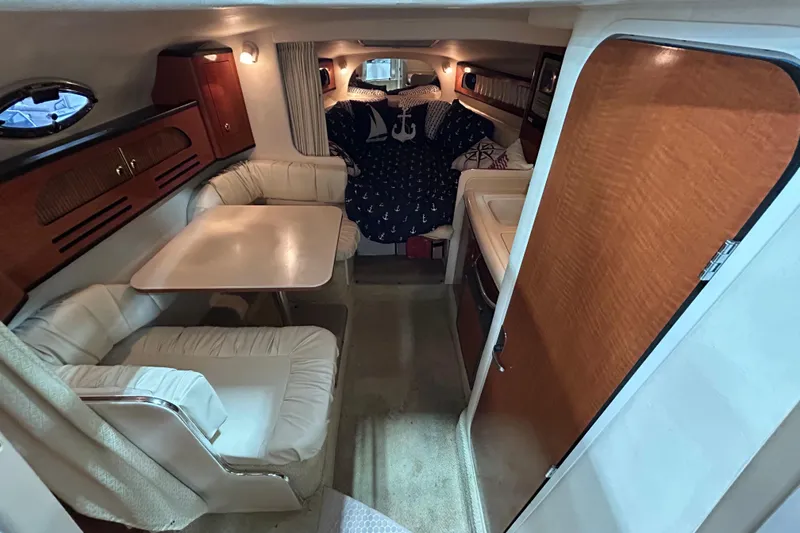 Slide: The Image of 2004 Sea Ray Sundancer 280 cabin interior with dining area and cozy sleeping quarters. - 13