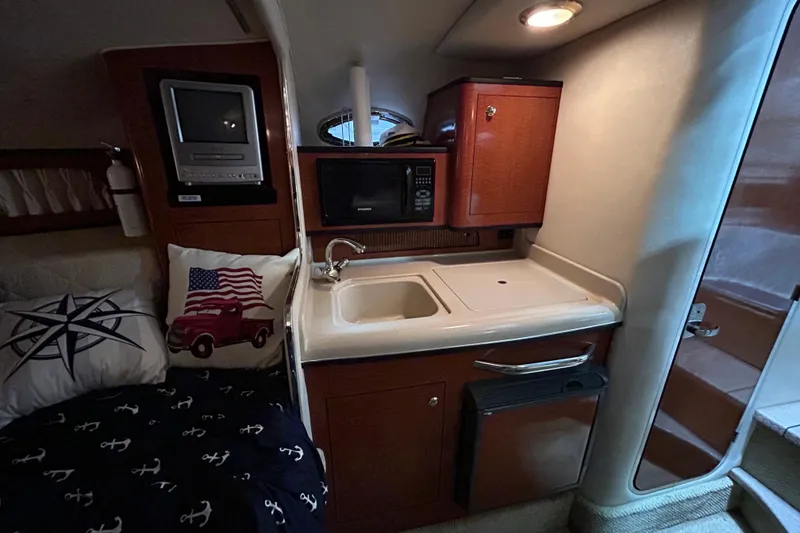 Slide: The Image of 2004 Sea Ray Sundancer 280 cabin interior with kitchenette and cozy bedding. - 16