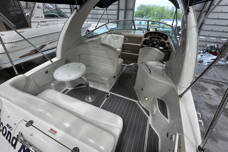 Slide: The Image of 2004 Sea Ray Sundancer 280 interior with seating, table, and helm in a boat garage. - 5