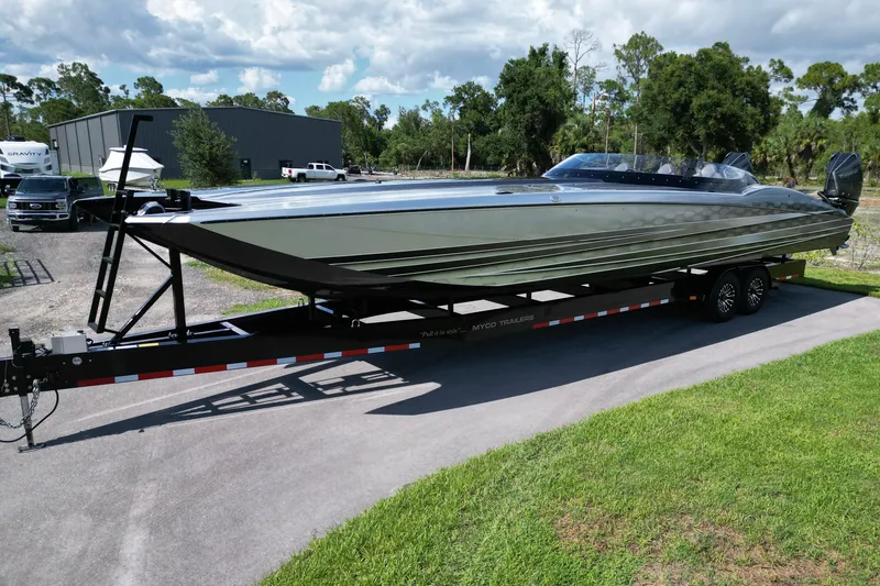 The Image of 2023 MTI 390X powerboat on trailer, sleek design, parked outdoors under cloudy sky. - 0