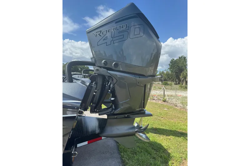 Slide: The Image of 2023 MTI 390X boat with Racing 450 outboard motor, parked on grass. - 14