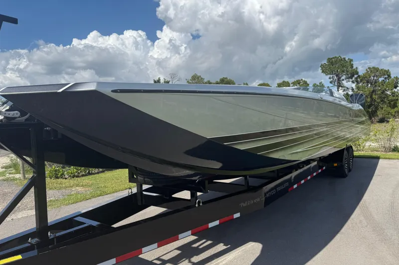 Slide: The Image of 2023 MTI 390X powerboat on trailer under cloudy sky, showcasing sleek design. - 23