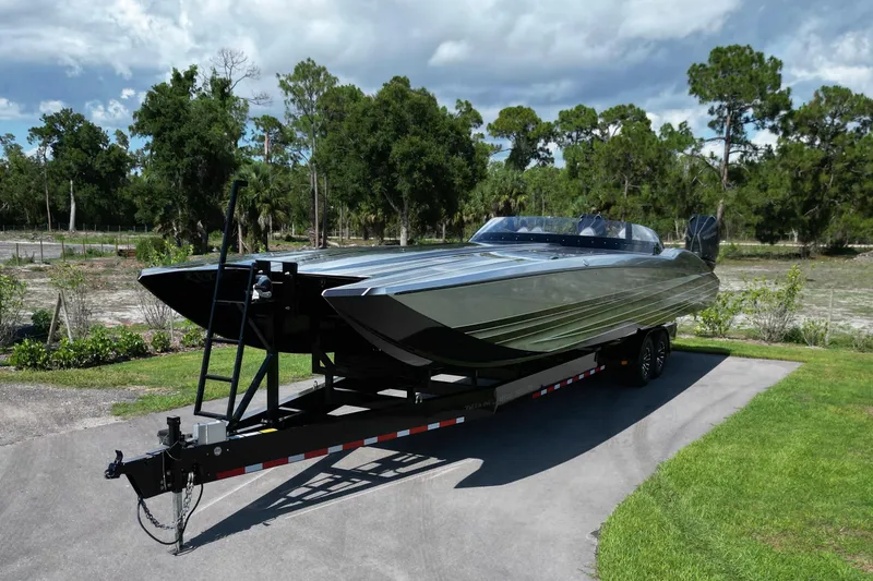 Slide: The Image of 2023 MTI 390X powerboat on trailer, parked outdoors with lush greenery background. - 6