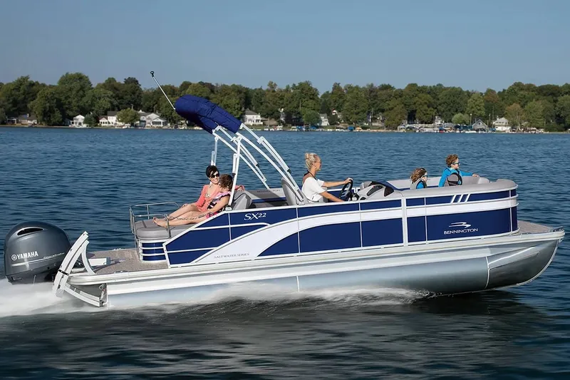 Slide: The Image of 2023 Bennington 20 SXSB pontoon boat cruising on a serene lake. - 8