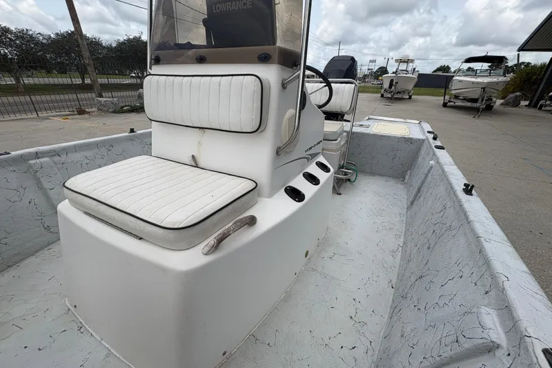 Slide: The Image of 2004 Kenner 18-V boat interior with white seating and console, parked outdoors. - 15