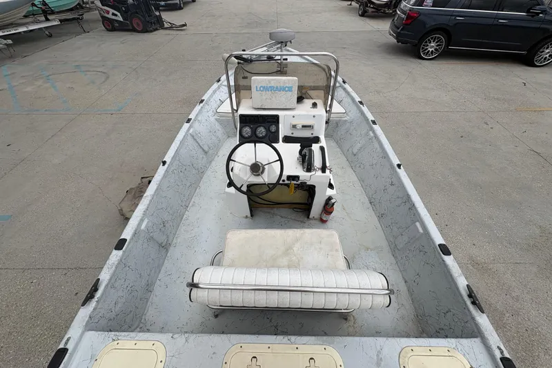 Slide: The Image of 2004 Kenner 18-V boat interior with steering wheel and control panel in a parking lot. - 17