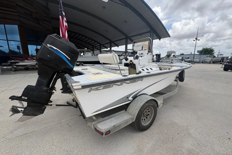 Slide: The Image of 2004 Kenner 18-V boat on trailer with outboard motor, parked outdoors. - 4