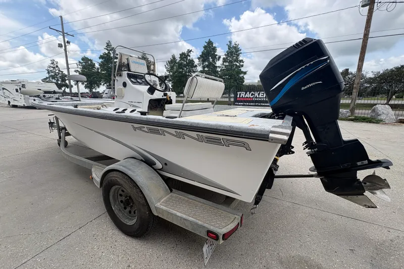 Slide: The Image of 2004 Kenner 18-V boat on trailer with outboard motor, parked outdoors. - 6