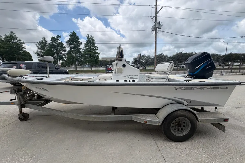 Slide: The Image of 2004 Kenner 18-V boat on trailer, parked outdoors under cloudy sky. - 7