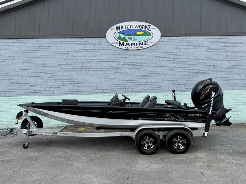 The Image of 2026 Xpress X19 Pro boat on trailer outside marine shop. - 1