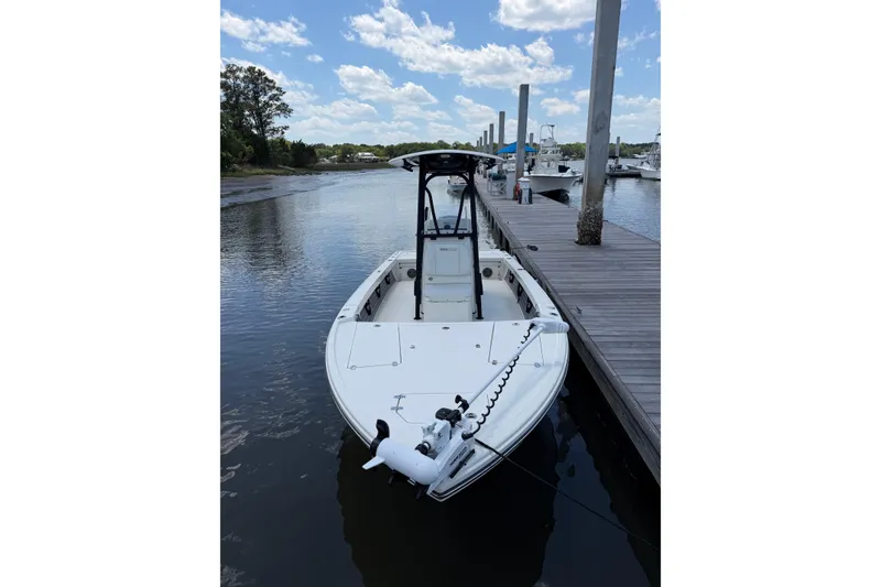Slide: The Image of 2024 Pathfinder 2500 Hybrid boat docked on a calm river under a blue sky. - 11