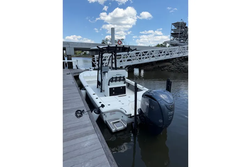 Slide: The Image of 2024 Pathfinder 2500 Hybrid boat docked by a wooden pier under a blue sky. - 16