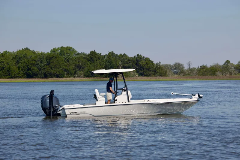 Slide: The Image of 2024 Pathfinder 2500 Hybrid boat cruising on a serene lake with lush green trees. - 2