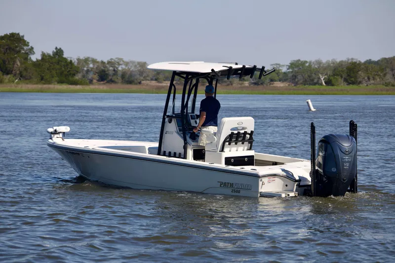 Slide: The Image of 2024 Pathfinder 2500 Hybrid boat cruising on a calm river with lush greenery. - 7