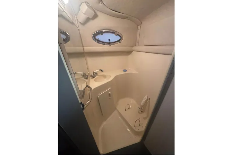 Slide: The Image of Bathroom interior of 1995 Sea Ray 250 Sundancer boat, featuring sink and porthole window. - 8