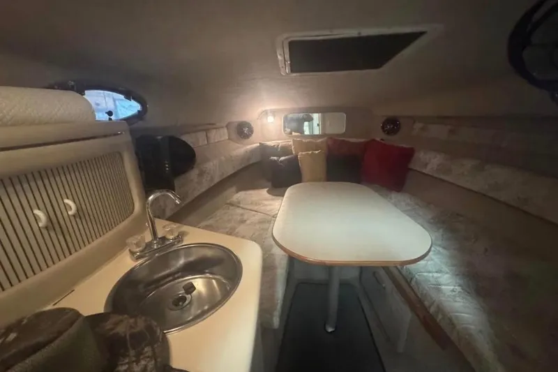 Slide: The Image of 1995 Sea Ray 250 Sundancer cabin interior with kitchenette, table, and seating area. - 9