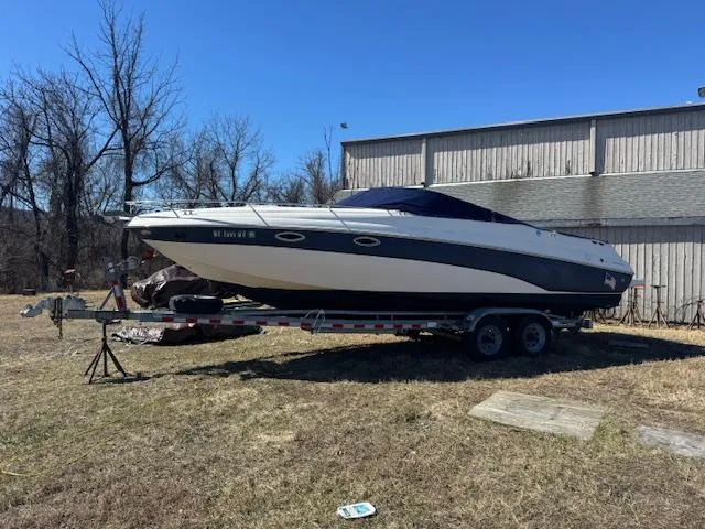 The Image of 2003 Rinker 282 Captiva Cuddy boat on trailer, parked outdoors near a building. - 1