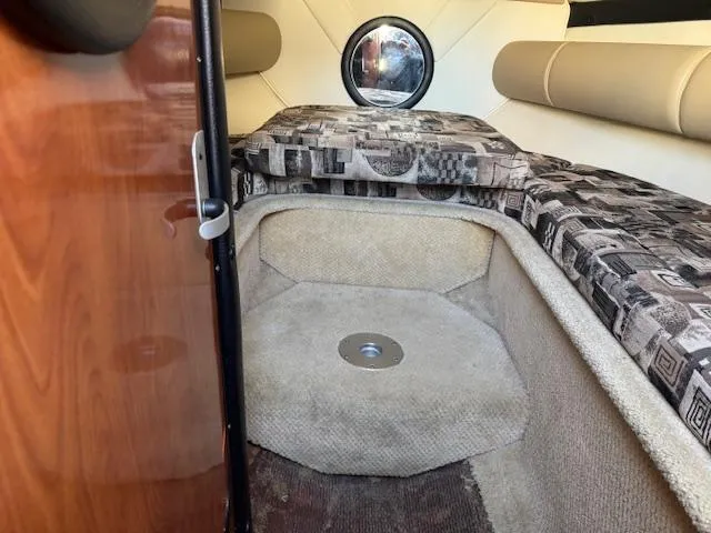 Slide: The Image of 2003 Rinker 282 Captiva Cuddy cabin interior with patterned cushions and round window. - 18