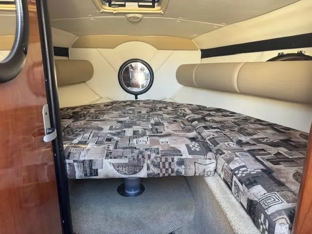 Slide: The Image of 2003 Rinker 282 Captiva Cuddy cabin interior with patterned upholstery and round window. - 19
