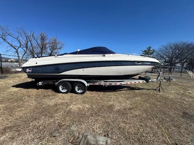 Slide: The Image of 2003 Rinker 282 Captiva Cuddy boat on trailer, parked on dry grass under clear blue sky. - 2