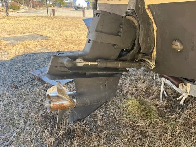 Slide: The Image of 2003 Rinker 282 Captiva Cuddy boat propeller and outdrive on dry grass. - 4