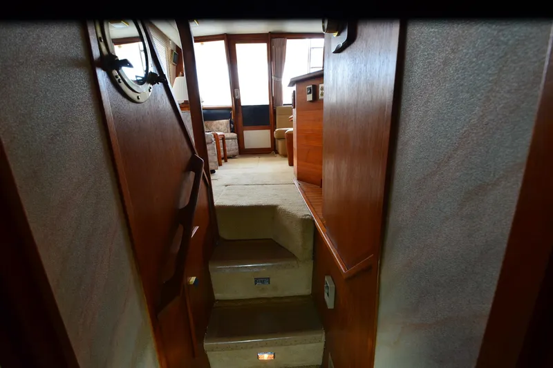 Slide: The Image of Interior view of 1989 Bayliner 4518 Motoryacht, featuring wooden stairs and cozy seating area. - 28