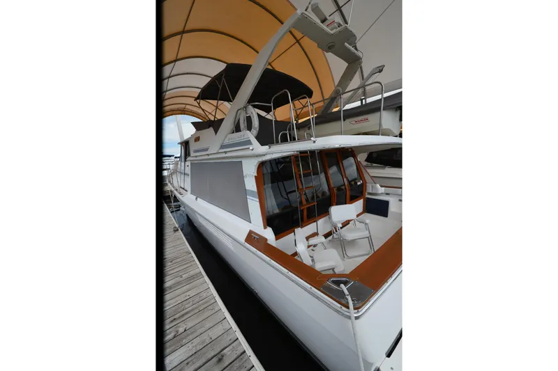 Slide: The Image of 1989 Bayliner 4518 Motoryacht docked under a canopy, showcasing its sleek design and spacious deck. - 3