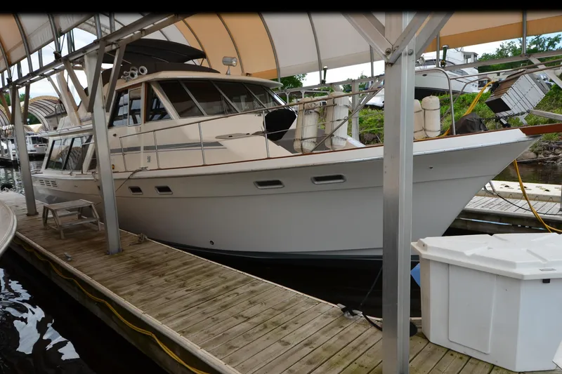 Slide: The Image of 1989 Bayliner 4518 Motoryacht docked under a canopy at a marina. - 4
