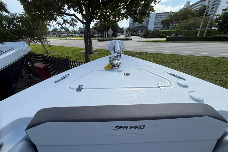 Slide: The Image of 2026 Sea Pro 225FLX Sandbar boat bow with seating and anchor, parked near a road. - 29