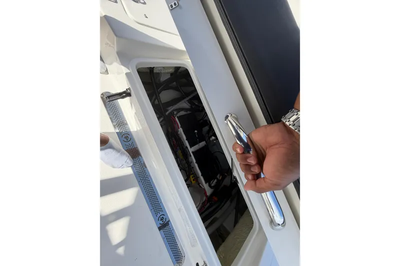Slide: The Image of Hand opening hatch on 2026 Sea Pro 225FLX Sandbar boat, revealing interior components. - 33