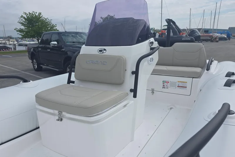 Slide: The Image of 2027 Grand Inflatables G420 boat with beige seating and sleek design in a marina setting. - 7