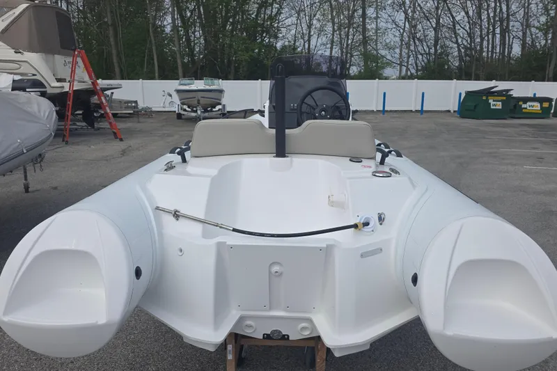 Slide: The Image of 2027 Grand Inflatables G420 boat in a parking lot, surrounded by trees and other boats. - 3