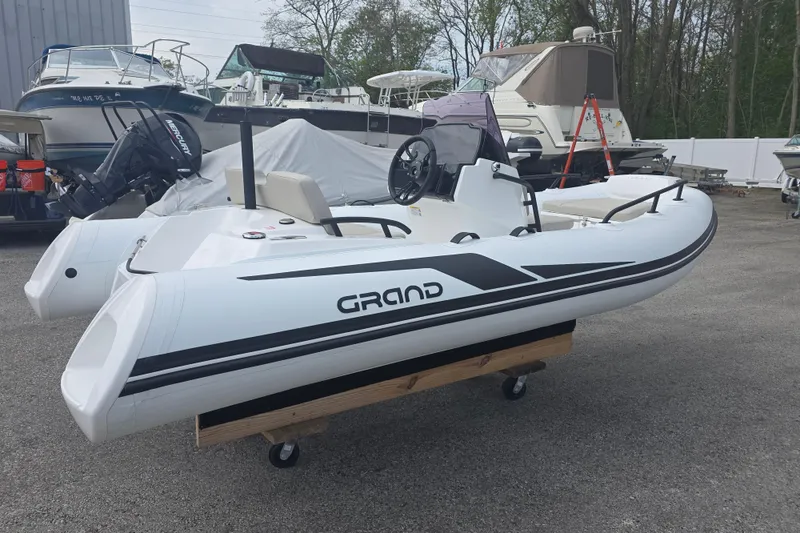 Slide: The Image of 2027 Grand Inflatables G420 boat displayed outdoors, surrounded by other vessels. - 2