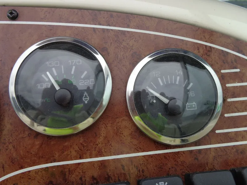 Slide: The Image of Dashboard of a 1999 Sea Ray Express Cruiser with temperature and battery gauges. - 30