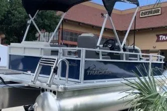 Slide: The Image of 2026 Sun Tracker Bass Buggy 16 XL Select pontoon boat with canopy, parked outdoors. - 4