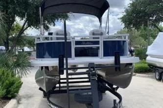 Slide: The Image of 2026 Sun Tracker Bass Buggy 16 XL Select pontoon boat on trailer, parked outdoors. - 1